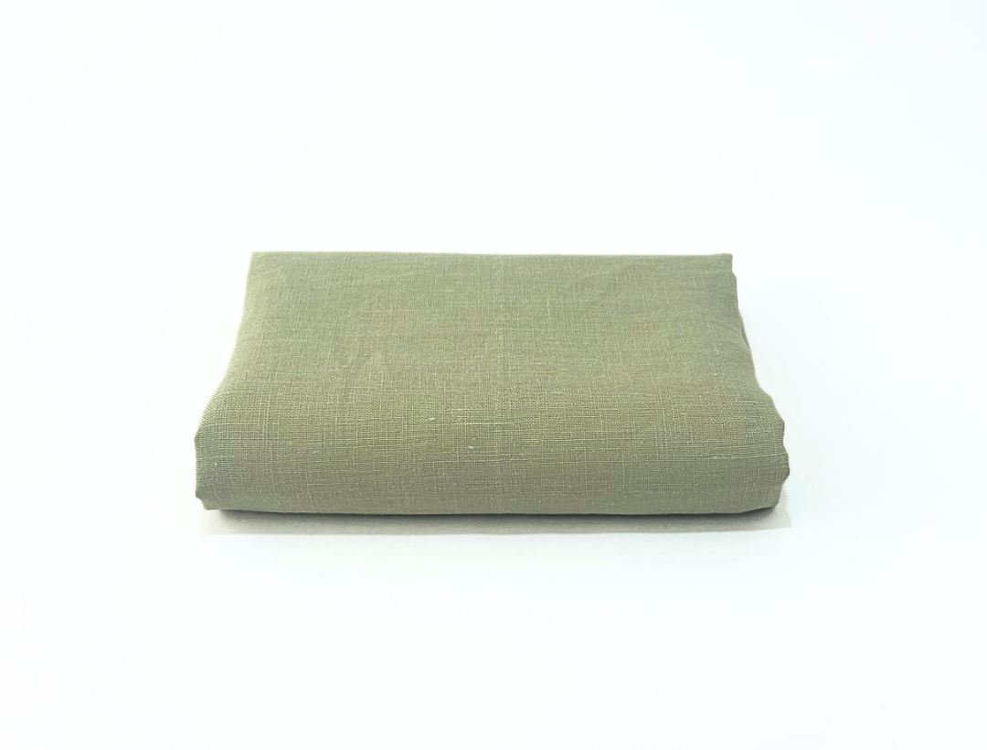 Folded sage green linen towel on a white background
