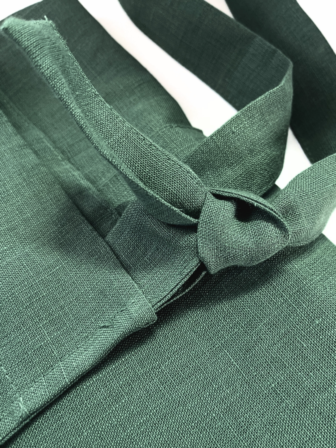 Close-up of olive green apron with a knot on a white background
