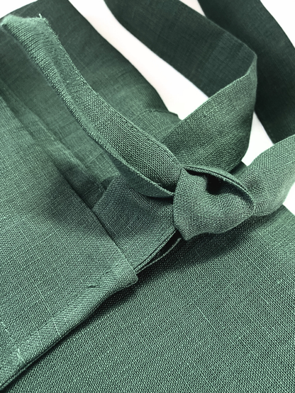 Close-up of olive green apron with a knot on a white background