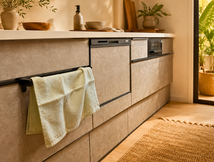 Beige kitchen cabinets with a towel hanging on a rack, natural light coming through a window.